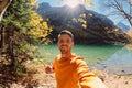 Selfie of happy man at the crystal lake in autumnal mountains. Mountain lake and hiker Royalty Free Stock Photo