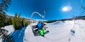 SELFIE: Happy snowboarder couple rides the chairlift on a sunny winter day.