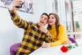Young couple having fun, making different grimaces and postures, while taking selfie with mobile phone in a cafe. Royalty Free Stock Photo