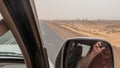 Selfie in the mirror of a moving off-road vehicle with a view of the Tombs and the cemetery of Old Dongola in the background