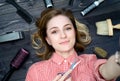 Selfie photo of happy smiling young woman in plaid shirt with scissors in hand and hairdresser tools