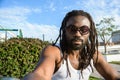 selfie portrait, young African man with dreadlocks, glasses and beard looking at the camera outdoors Royalty Free Stock Photo