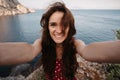 Selfie-portrait of a young woman against the background of the sea at the cliff. The girl smiles at the camera. The Royalty Free Stock Photo