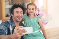 Selfie session with Dad. a happy father and daughter taking a selfie together on a mobile phone at home. Royalty Free Stock Photo