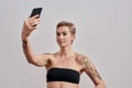 Selfie Time. Attractive tattooed woman with pierced nose and short hair taking a picture of herself, selfie using Royalty Free Stock Photo
