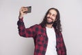 Selfie time! Handsome young man in red checkered shirt and long Royalty Free Stock Photo