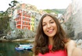 Selfie woman taking self portrait with typical italian village on the background. Girl holding smartphone camera to take a picture Royalty Free Stock Photo
