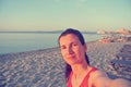 Selfie of a young woman on the beach at sunset; faded, retro style