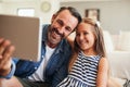 Selfies with my little Miss Sunshine. an adorable little girl taking selfies with her father on a digital tablet at home Royalty Free Stock Photo