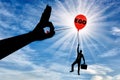 A selfish businessman clings to a balloon called the ego and a big hand with a needle intends to burst it Royalty Free Stock Photo