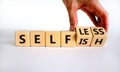 Selfish or selfless symbol. Businessman turns cubes and changes the word `selfish` to `selfless`. Beautiful white background,