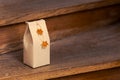 Selfmade gift box out of old beverage carton decorated with star shaped cut out dried roange peel standing on wooden stairs