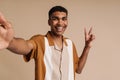 Selfportrait of young handsome smiling african man doing victory gesture