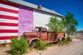 SELIGMAN, AZ - JUNE 29, 2018: Old rusty vintage truck under a painted american flag on the wall Royalty Free Stock Photo