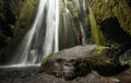 Seljalandsfoss, Iceland - Lone person in red explores Gljufrafoss cave waterfall