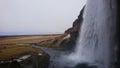 Side view by looking at Seljalandsfoss, a great waterfall side by side with a cloudy sky