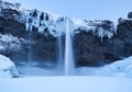 Seljalandsfoss waterfall, Iceland. Icelandic winter landscape.  High waterfall and rocks. Snow and ice. Powerful stream of water f Royalty Free Stock Photo