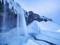 Seljalandsfoss waterfall, Iceland. Icelandic winter landscape.  High waterfall and rocks. Snow and ice. Powerful stream of water f Royalty Free Stock Photo
