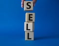 Sell symbol. Concept word Sell on wooden cubes. Businessman hand. Beautiful blue background. Business and Sell concept. Copy space