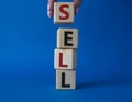 Sell symbol. Concept word Sell on wooden cubes. Businessman hand. Beautiful blue background. Business and Sell concept. Copy space