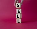 Sell symbol. Concept word Sell on wooden cubes. Businessman hand. Beautiful red background. Business and Sell concept. Copy space