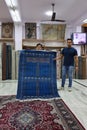 Seller of antique carpets shows colorful embroidered bedspreads at the marketplace of oriental bazaar