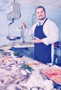 Seller behind scales and fish counter showing fish