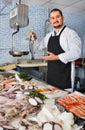 Seller behind scales and fish counter showing fish