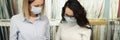 Seller with buyer in medical protective masks communicate in fabric store