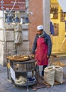 seller of charcoal roasted chestnuts cooking in the street of the city of Rome with a red apron