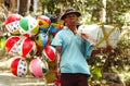 The seller of children`s toys balloons peddles his merchandise in the village of Ngebel