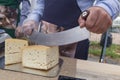 Seller cutting delicious cheese on table in store Royalty Free Stock Photo