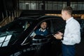 The seller demonstrates the interior of the car to buyers. Caucasian couple chooses a car.