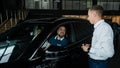 The seller demonstrates the interior of the car to buyers. Caucasian couple chooses a car.