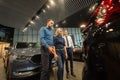 The seller demonstrates the interior of the car to buyers. Caucasian couple chooses a car.