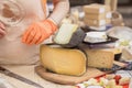 Seller girl sells cheese. Female hands. Cut cheese heads on wooden market board. Selective focus. Royalty Free Stock Photo