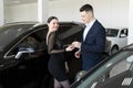 Seller gives the buyer the keys to a new car in the showroom. Royalty Free Stock Photo