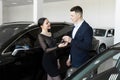 Seller gives the buyer the keys to a new car in the showroom. Royalty Free Stock Photo