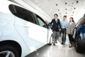 Seller Guy Helping Family Couple Choose Car In Dealership Showroom Royalty Free Stock Photo