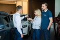 The seller hands over the car keys to the buyers. The couple bought a new car.