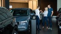 The seller hands over the car keys to the buyers. The couple bought a new car.