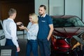 The seller hands over the car keys to the buyers. The couple bought a new car.