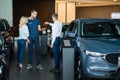 The seller hands over the car keys to the buyers. The couple bought a new car.