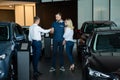 The seller hands over the car keys to the buyers. The couple bought a new car.