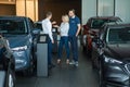 The seller hands over the car keys to the buyers. The couple bought a new car.