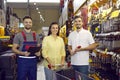 Seller and happy couple of buyers who buy tools for repair in hypermarket of building materials. Royalty Free Stock Photo