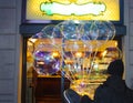 Seller of many transparent balloons in front of a bright party shop