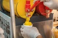 Seller pours frozen juice or serbet into a once-only glass from the machine.