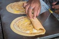 Seller rolling Khanom Tokyo thin flat pancake Thai street snack