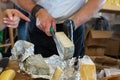 Seller& x27;s hands cut off a piece of cheese. Russian farmer& x27;s cheeses from the manufacturer. Assortment of tasty